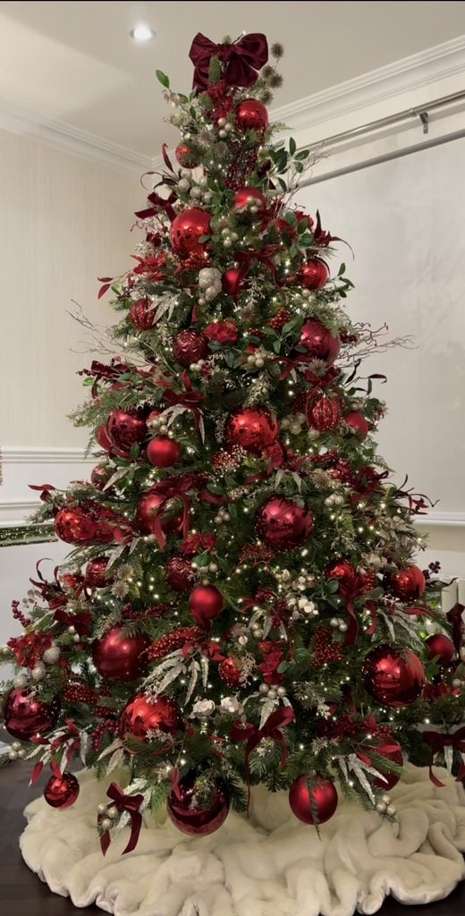 Rich burgundy Christmas tree design with layered red ornaments, greenery, berries and elegant textural holiday details.