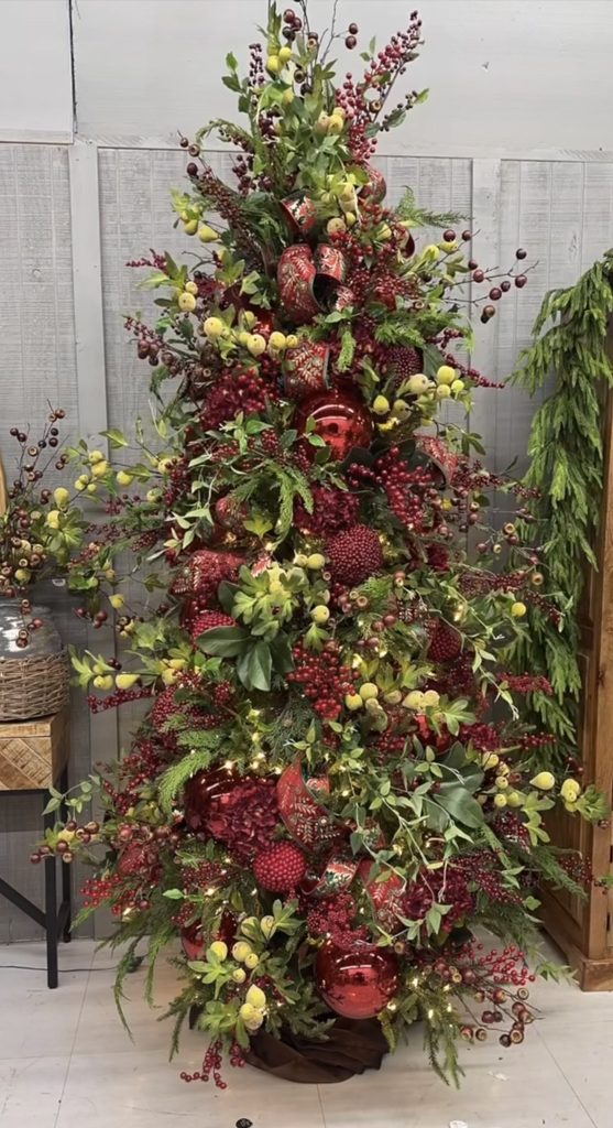 Elegant burgundy Christmas tree styling with deep red ornaments, dimensional greenery and dramatic holiday accents.