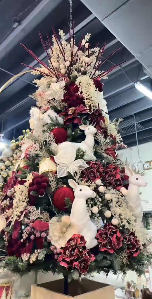 Whimsical burgundy Christmas tree styled with playful deep red decorations, layered ornaments and festive greenery.
