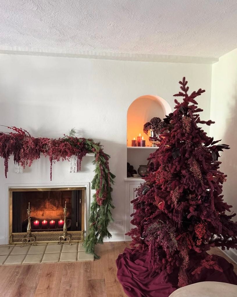 Burgundy Christmas tree styled from top to bottom in deep wine tones with matching burgundy branches, berries, floral accents and a burgundy tree skirt.