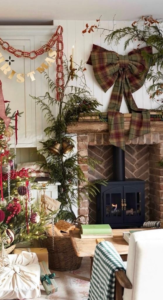 Christmas fireplace mantel decorated with greenery and an oversized statement bow as the dramatic focal point.