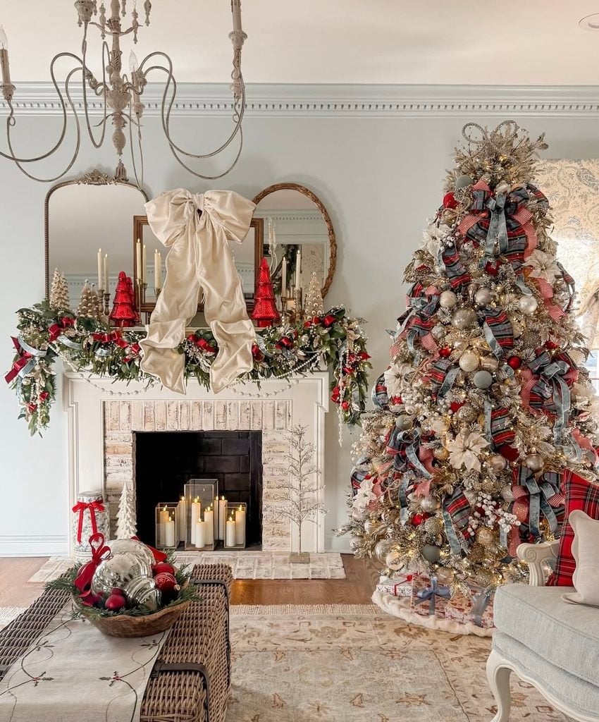 Christmas fireplace mantel decorated with layered greenery, ornaments, candles, and festive seasonal details.