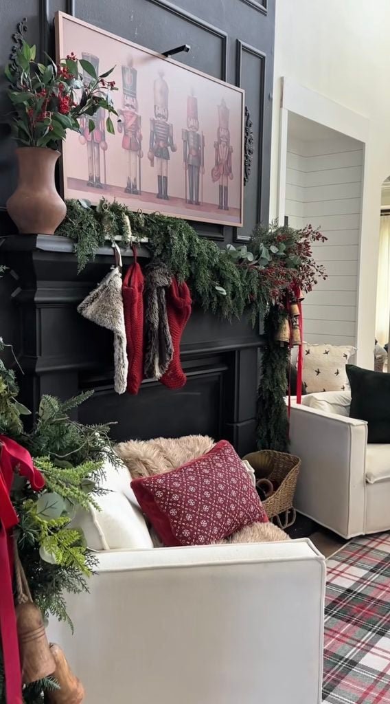 Christmas fireplace mantel decorated with greenery and seasonal accents beneath framed artwork used as the focal point.