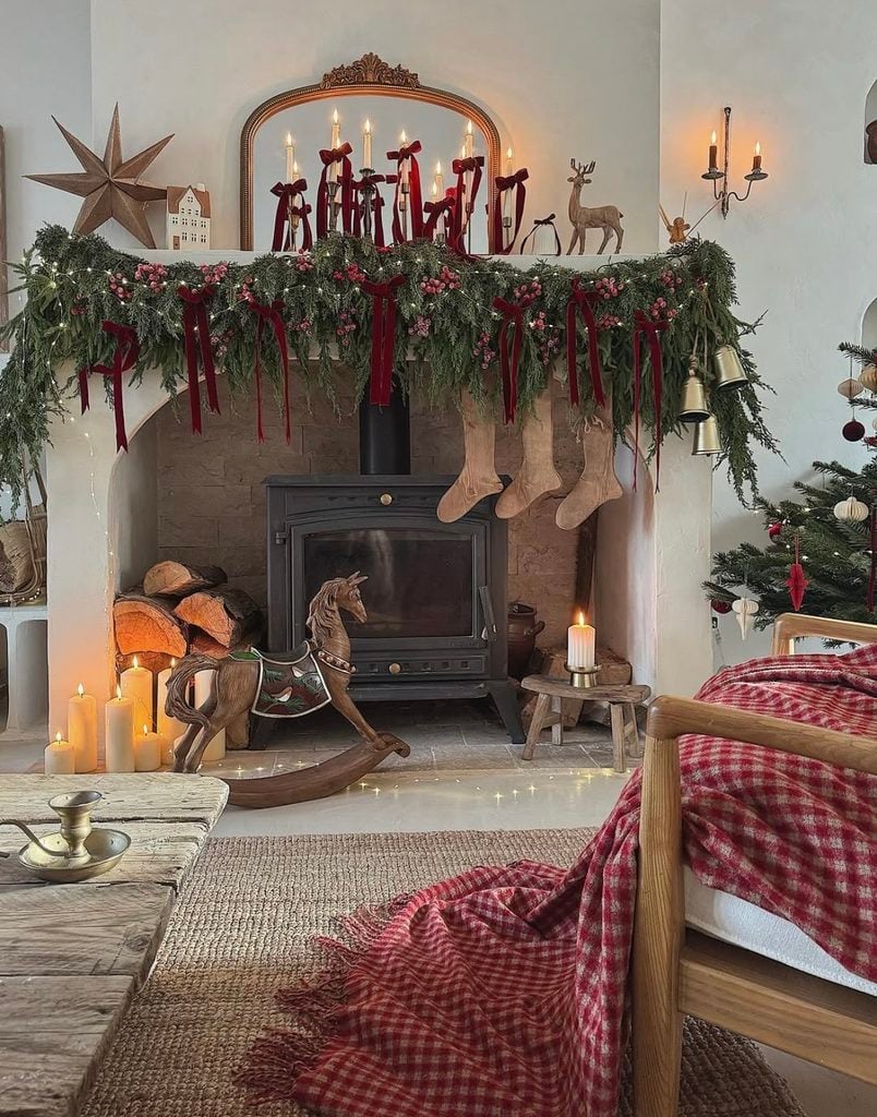 Christmas fireplace mantel decorated with hanging stockings, greenery, candles, and cozy holiday accents.