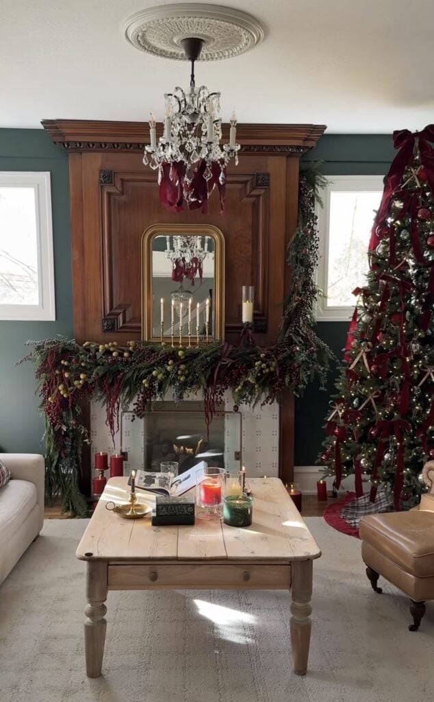 Classic Christmas fireplace mantel with candles, burgundy ribbon, greenery, and traditional holiday decor.
