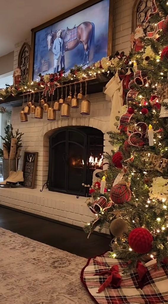 Christmas fireplace mantel decorated with greenery, hanging bells, stockings, and natural seasonal accents.