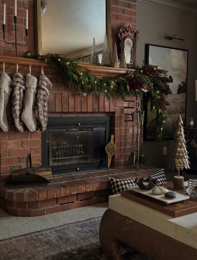 Elegant Christmas mantel with asymmetrical three-quarter garland on brick fireplace and understated holiday styling.