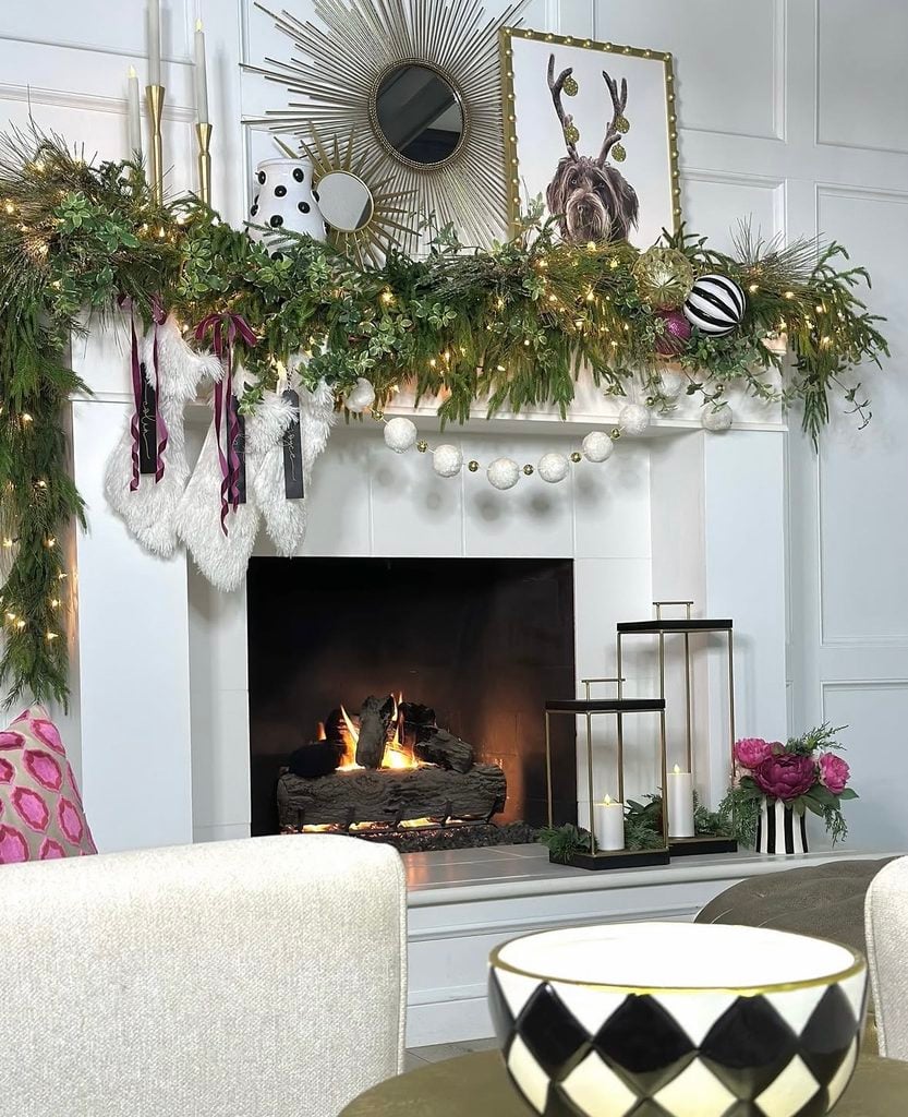 Christmas fireplace mantel decorated with greenery, stockings, candles, and layered festive accents in a cozy living room.