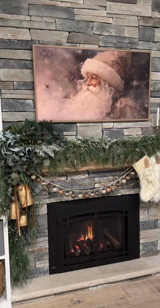 Christmas fireplace mantel idea featuring layered greenery, candles, stockings, and festive seasonal decorations.