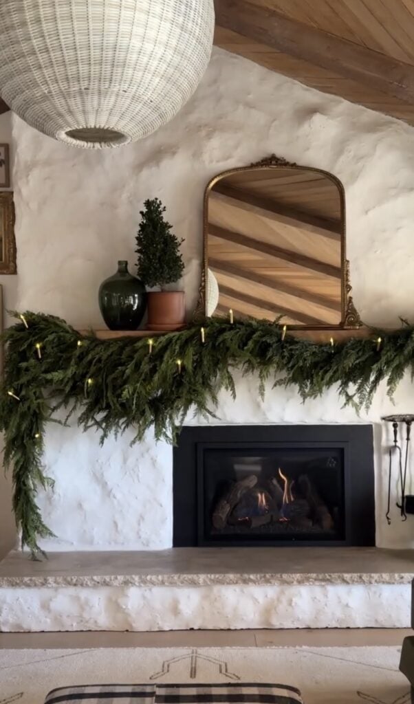 Christmas mantel with lush greenery, glowing candles, and simple classic holiday decor.