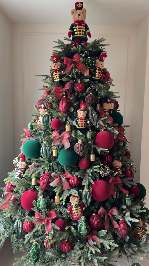 Ralph Lauren Christmas tree decorated with teddy bear nutcrackers, red and green ornaments, tartan bows, brass bells, and traditional plaid holiday accents.