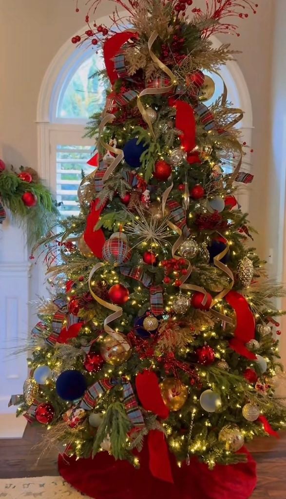 Ralph Lauren Christmas tree layered with tartan ribbon, red velvet ribbon, navy and gold ornaments, metallic accents, greenery, berries, and textured holiday decorations.