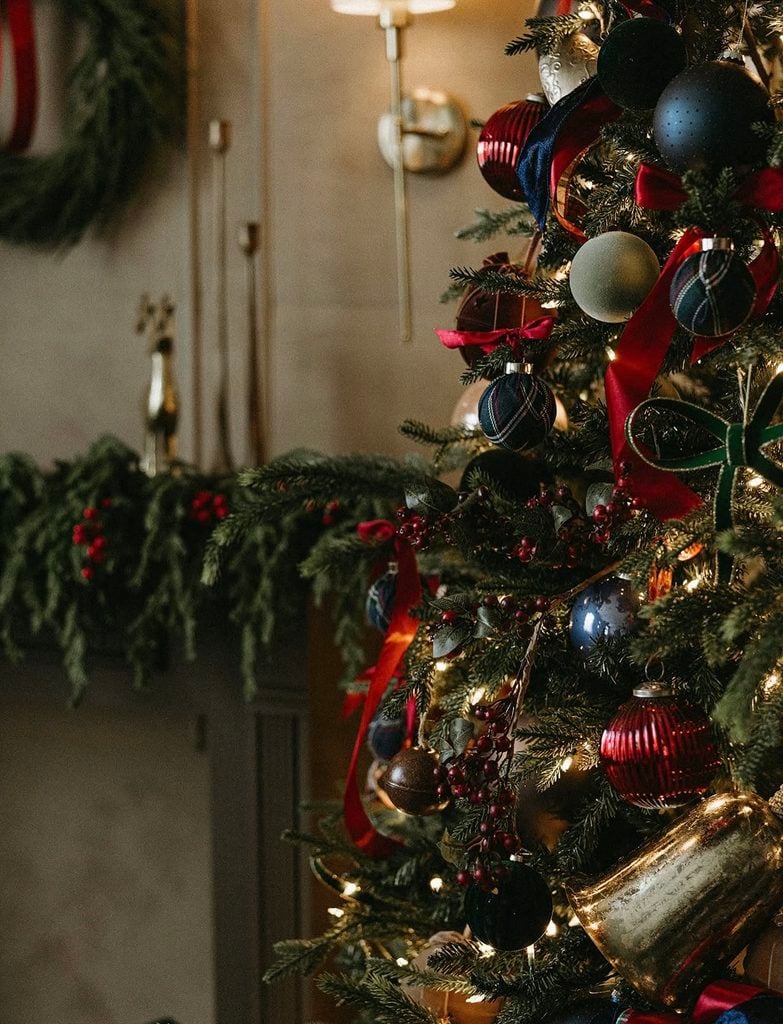 Ralph Lauren Christmas tree decorated with deep navy, burgundy, hunter green, and red ornaments, plaid accents, velvet ribbon, red berries, and warm white lights.