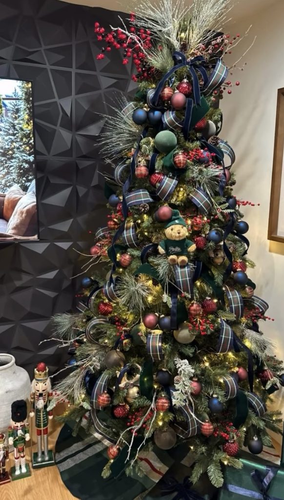 Ralph Lauren-style Christmas tree decorated with rich red, navy, and green ornaments, plaid ribbon, velvet accents, berries, metallic details, and warm white lights.