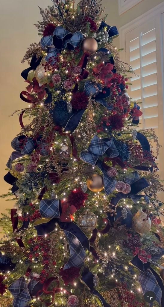 Ralph Lauren Christmas tree decorated with navy velvet ribbon, blue plaid bows, burgundy ornaments, red berries, gold accents, and warm white lights.