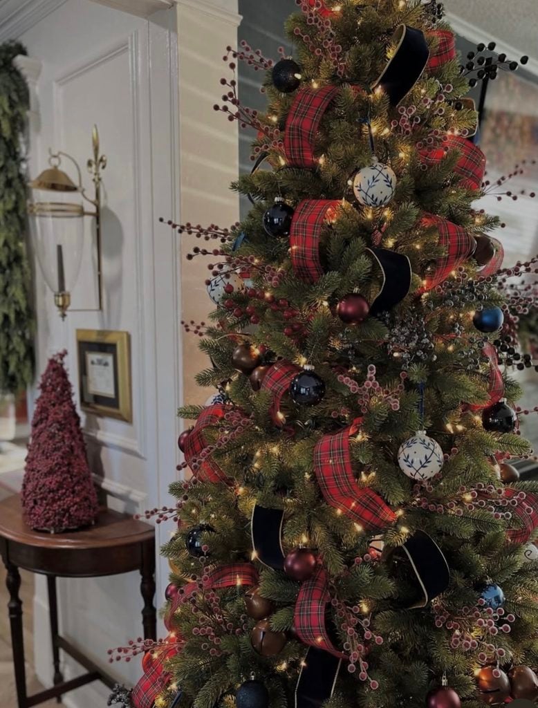 Traditional Ralph Lauren Christmas tree decorated with red tartan ribbon, black velvet ribbon, burgundy and navy ornaments, berry sprays, and white porcelain-inspired ornaments.