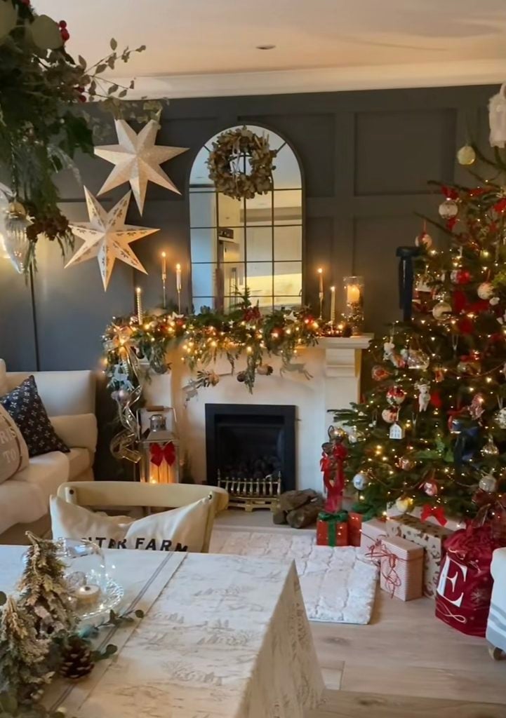 Christmas mantel decorating idea featuring layered greenery, candles, stockings, and festive accents around the fireplace.