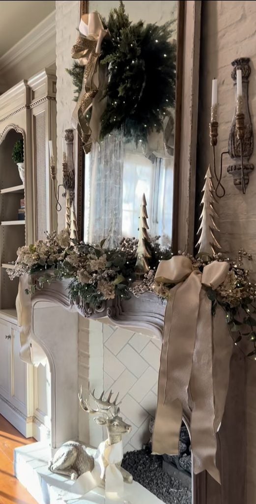 Neutral Christmas fireplace mantel styled with evergreen garland, candles, natural textures, and understated holiday decorations.