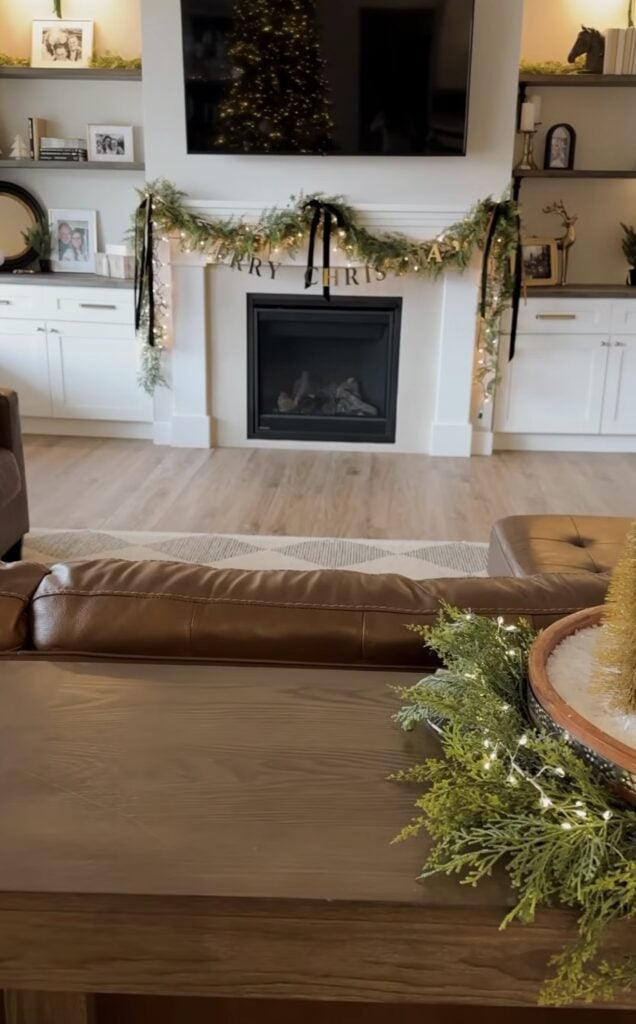 Simple Christmas mantel with ribbon, greenery, and Merry Christmas decor in a classic holiday style.