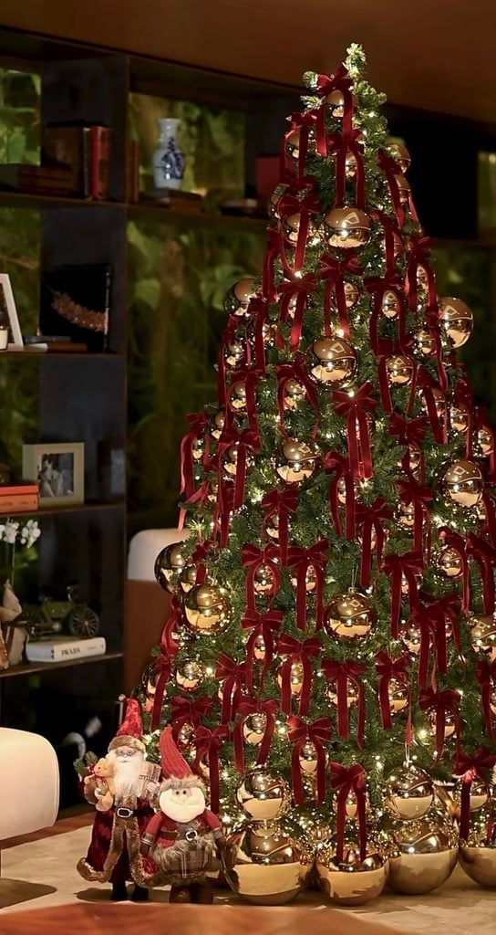 Victorian-inspired Christmas tree decorated with burgundy velvet bows, oversized gold ornaments and warm white lights.
