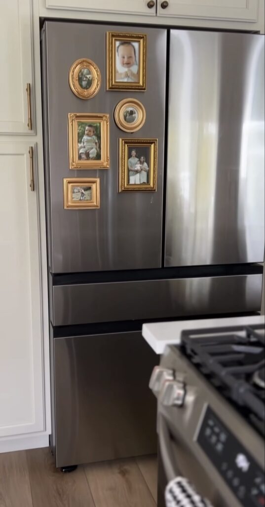Simple fridge gallery wall on a stainless steel refrigerator with family photos displayed in a collection of small ornate gold frames.