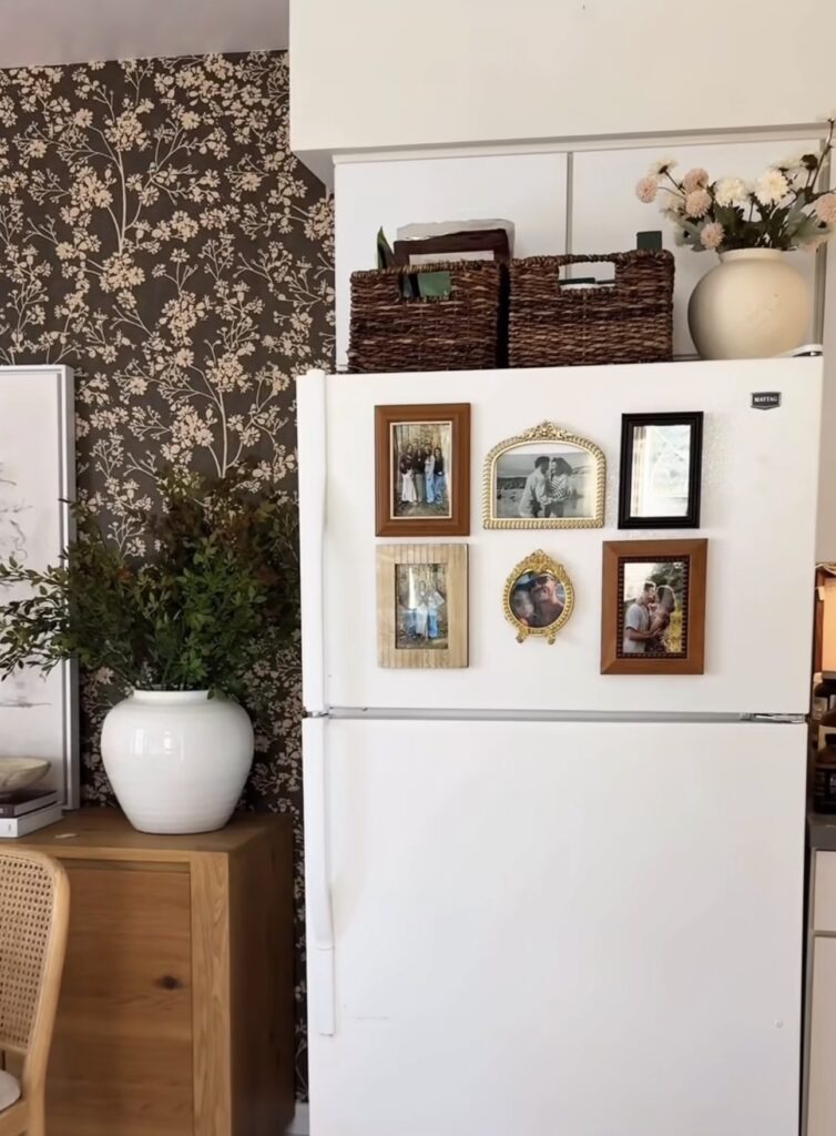 Fridge gallery wall on a white refrigerator with family photos in mismatched wood, black and ornate gold frames in a warm vintage-inspired kitchen.