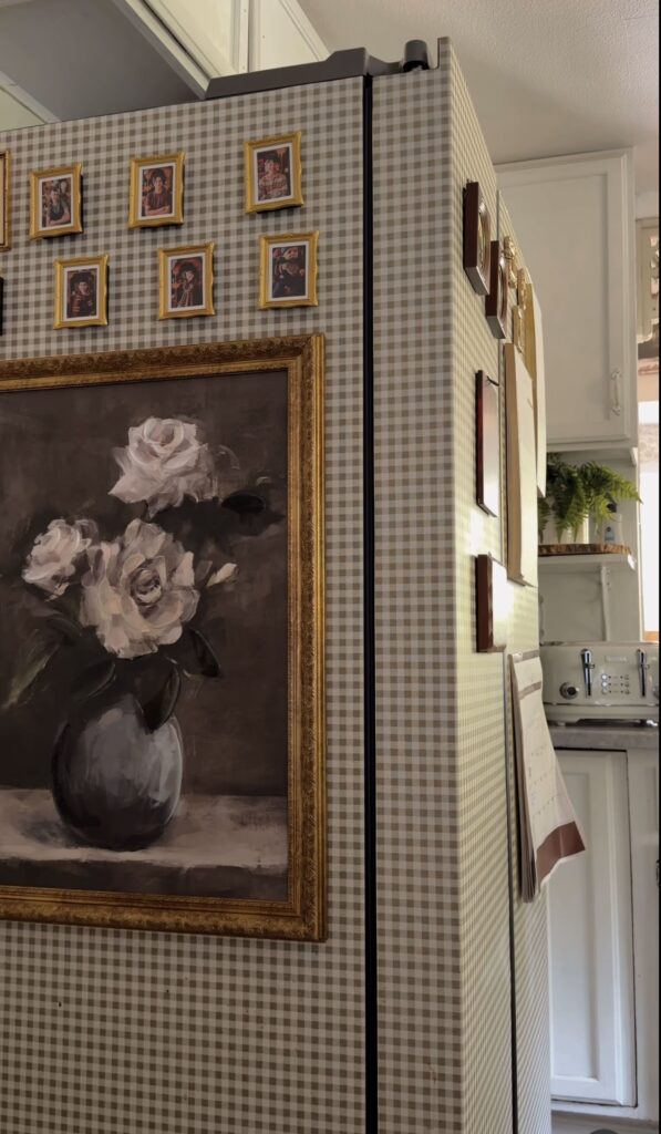 Wallpapered fridge gallery wall with beige gingham covering, tiny gold-framed photos and a large vintage floral painting extending across the refrigerator.