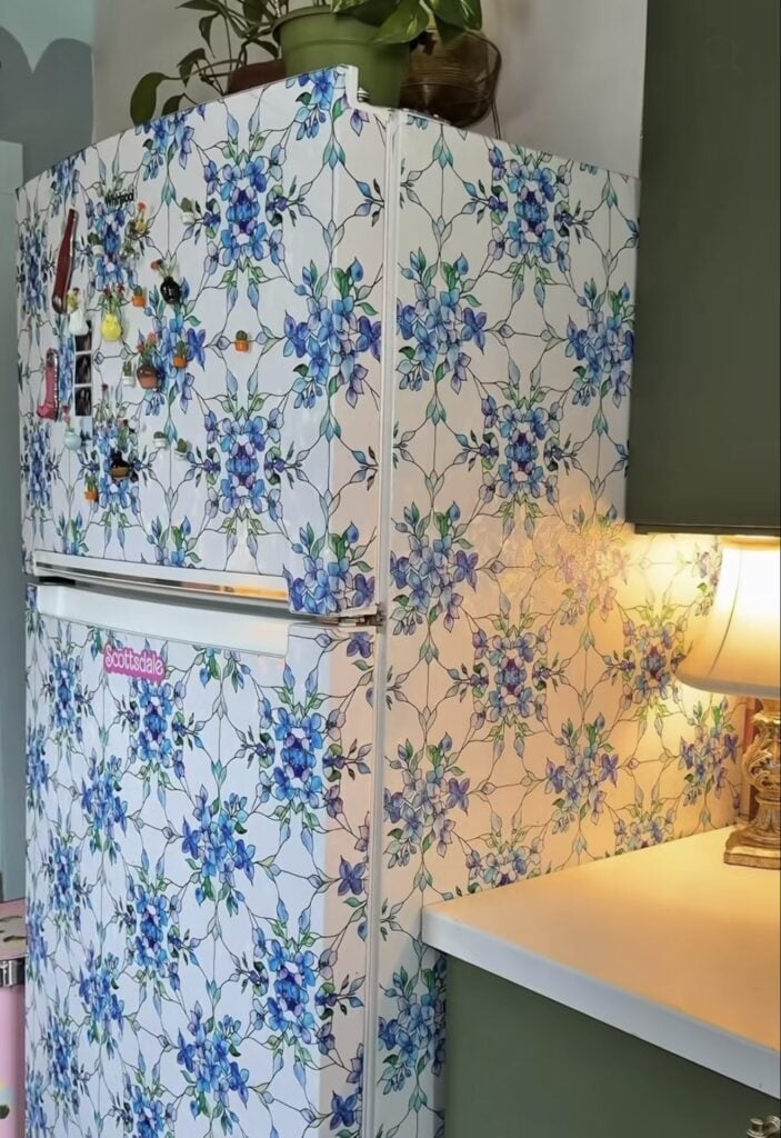 Refrigerator covered in blue floral wallpaper as a decorative kitchen accent.