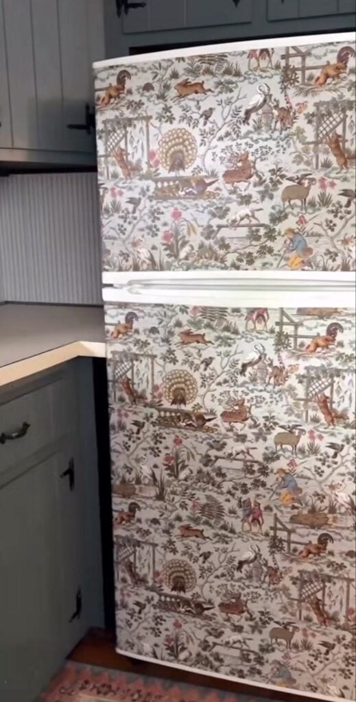 Refrigerator covered in wallpaper that coordinates with the surrounding kitchen wall pattern.
