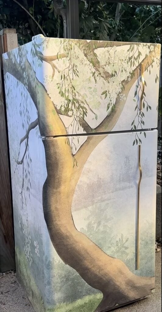 Refrigerator covered in botanical tree-inspired wallpaper as a creative kitchen decorating idea.