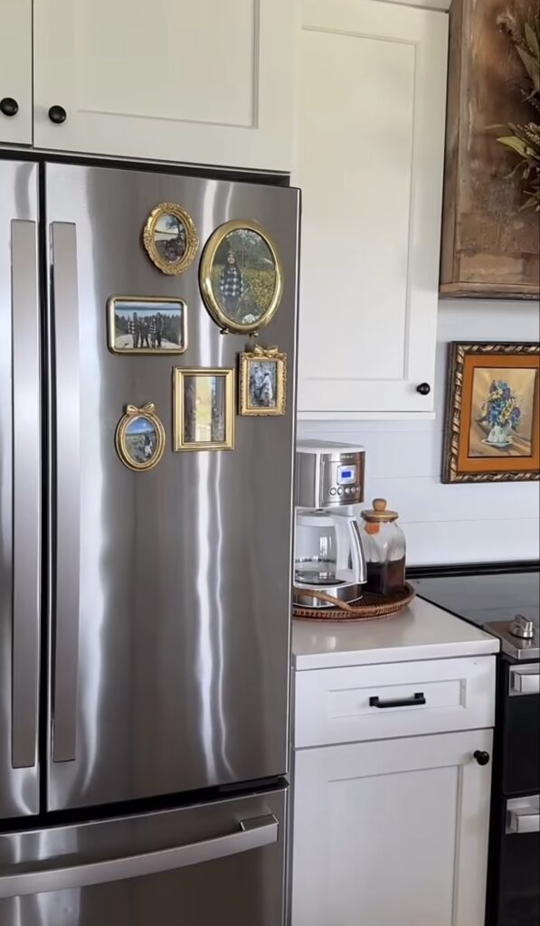 Simple fridge gallery wall on a stainless steel refrigerator with family photos and outdoor pictures displayed in mismatched vintage-style gold frames.
