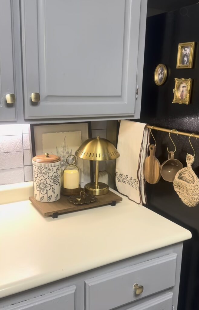 Family photo gallery wall on the side of a dark refrigerator with mismatched black, wood and ornate gold frames, including family photos and an ultrasound picture.