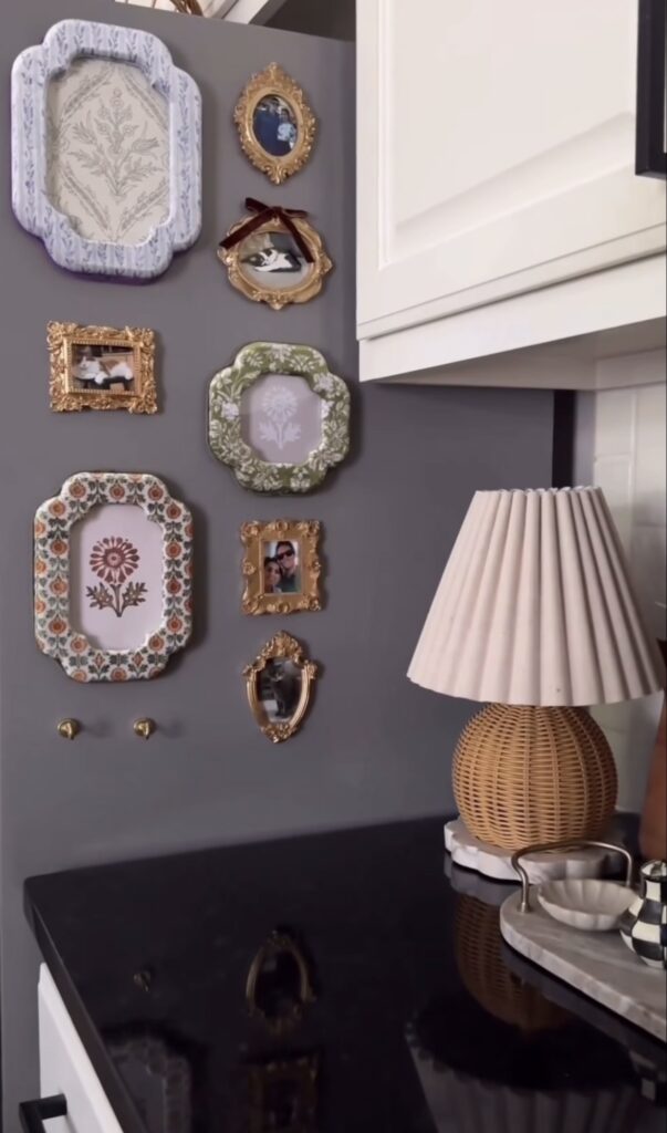 Fridge gallery wall arranged on the side of a gray refrigerator with a mix of floral frames, ornate gold frames, family photos and vintage-style artwork.