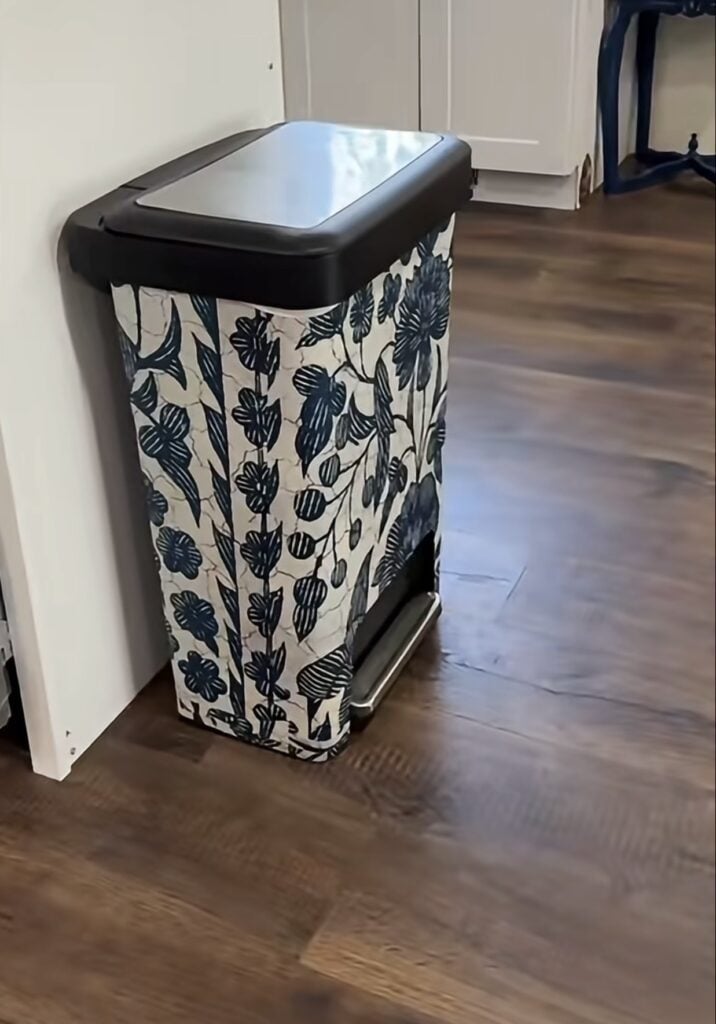 Ordinary kitchen trash can transformed with decorative peel-and-stick wallpaper.