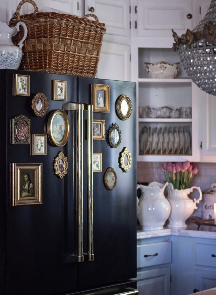Dark blue refrigerator decorated with an elegant fridge gallery wall of vintage gold frames, botanical art, portraits and small mirrors.