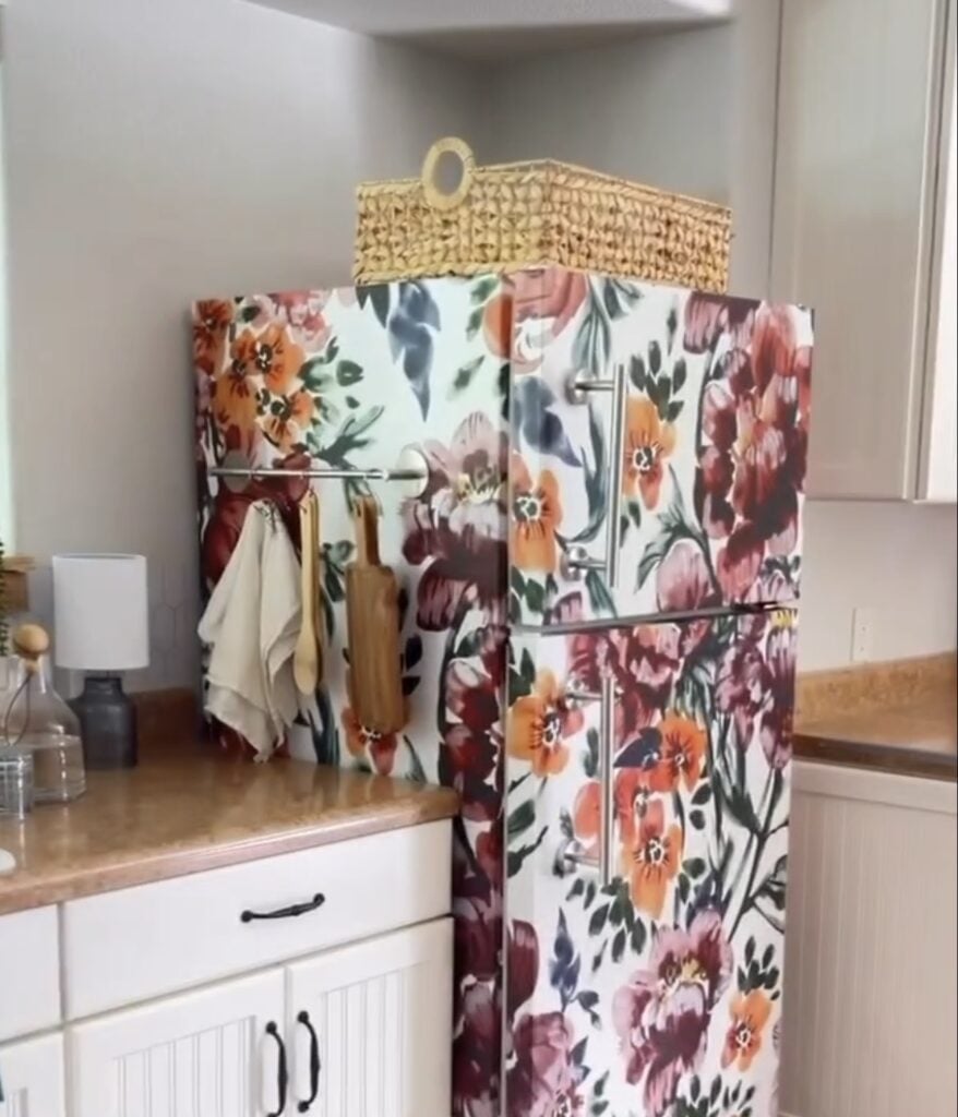 White refrigerator transformed with oversized floral wallpaper in burgundy, orange and pink.