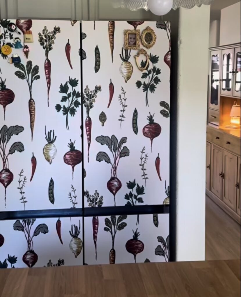 Refrigerator decorated with illustrated vegetable wallpaper featuring carrots, beets and other garden produce.