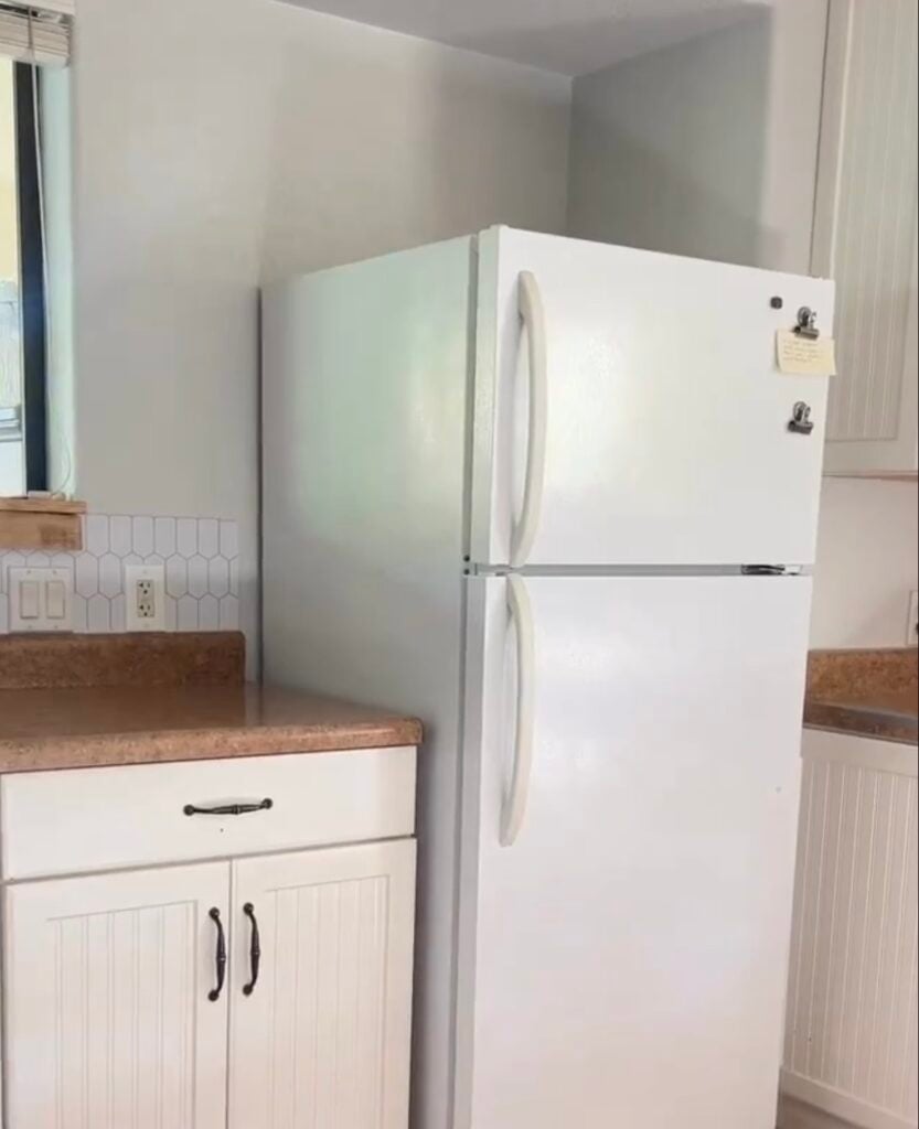 Plain white refrigerator in a kitchen before a peel-and-stick wallpaper makeover.